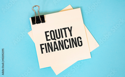 Text EQUITY FINAnCING on sticky notes with copy space and paper clip isolated on red background.Finance and economics concept.