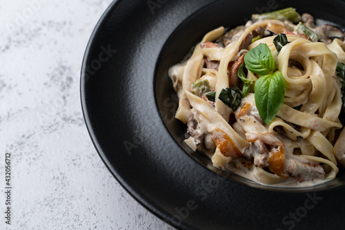 Nourishing creamy pasta with vegetables and roasted beef,  decorated with fresh basil