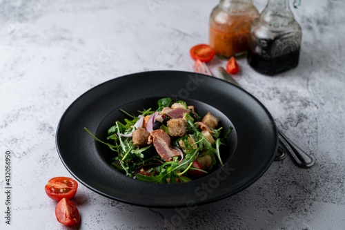 Arugula and bacon salad in a black wide dish