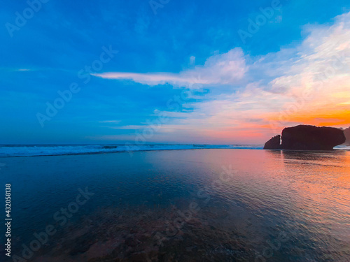 One rock creeping out of the ocean on transparent water at Kukup beach photo