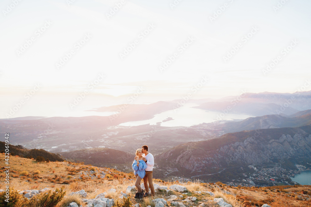 Man hugs a woman in a blue sweater by the shoulders against the background of Mount Lovcen, Kotor bay, Montenegro