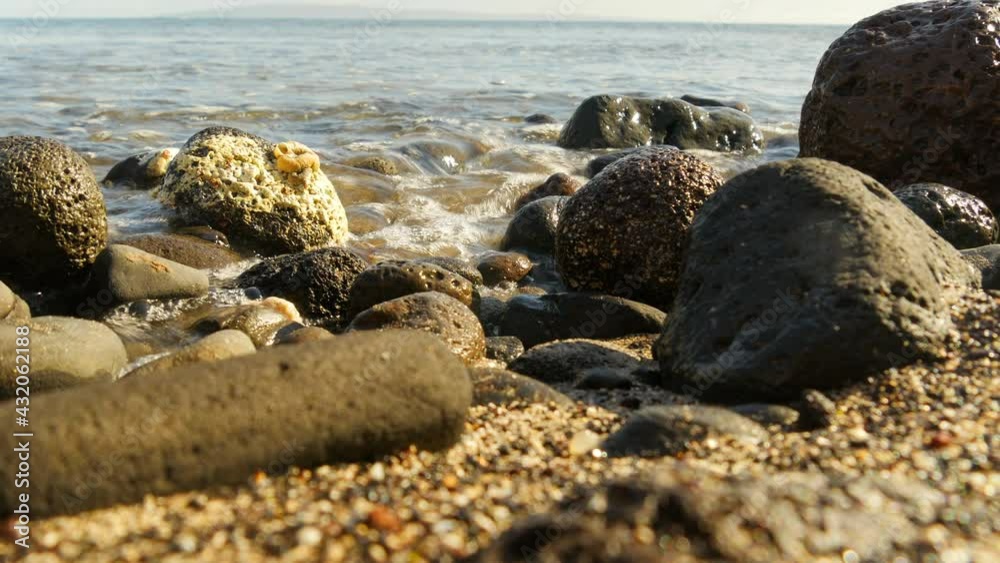 Rocky stony coral sea beach with dramatic sunlight, waves breaking on the shore Rocky stony coral sea beach with dramatic sunlight, waves breaking on the shore