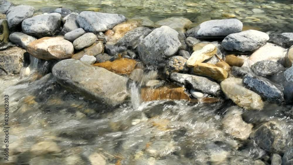Moving fresh clean water getting by a small dam made of rocks, medium shot Moving fresh clean water getting by a small dam made of rocks, medium shot