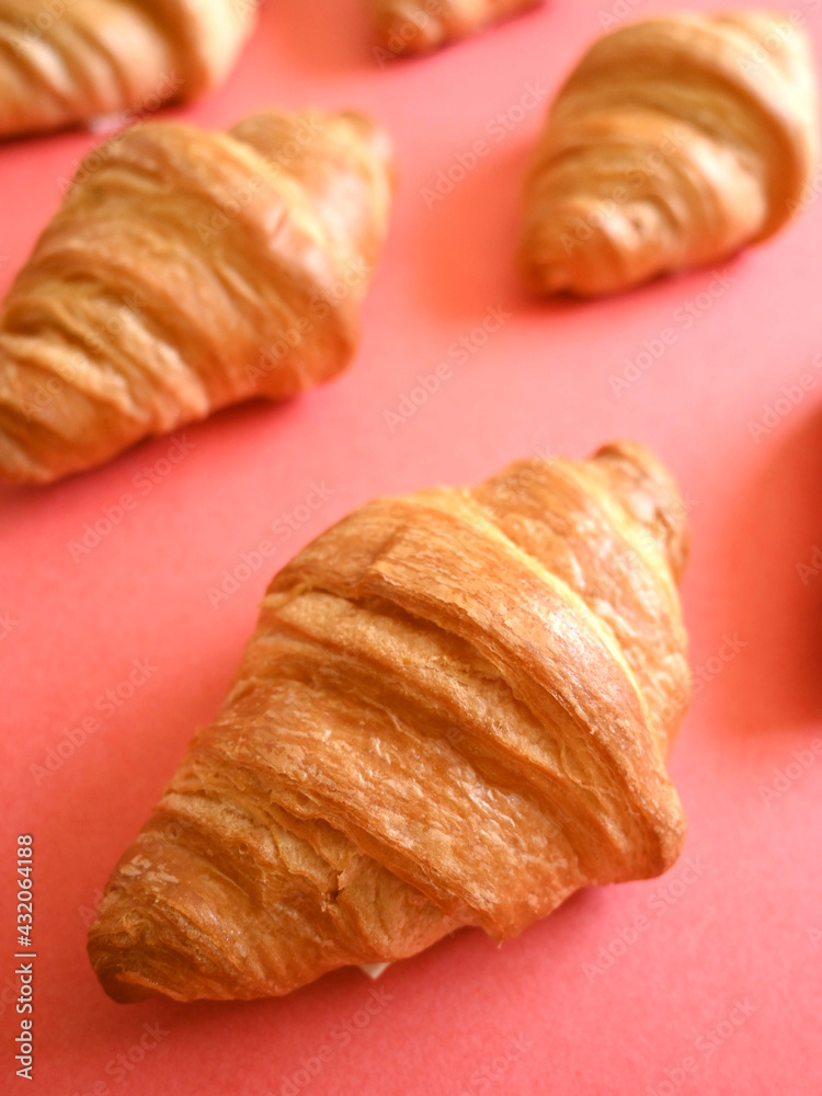 Front shot of pattern of delicious homemade golden croissants on coral background