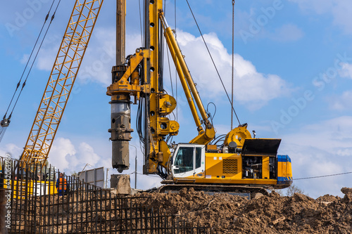 Yellow hydraulic drilling rig on a high-rise building construction site. Installing a bored piles with a casing string. Foundation skyscraper photo