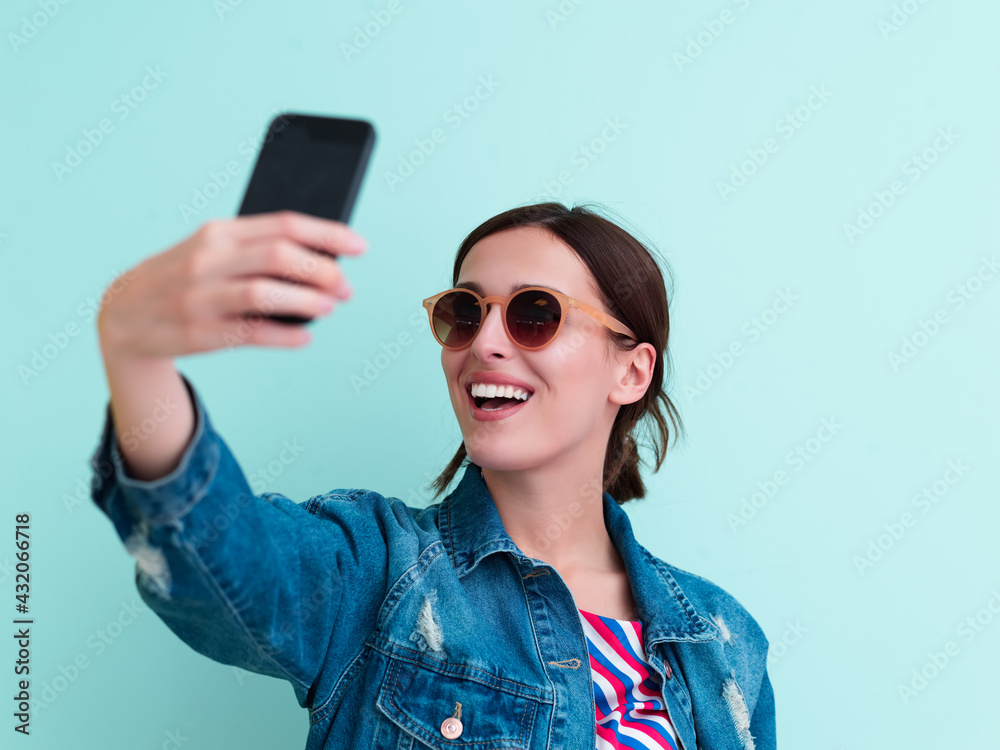 Portrait of young girl taking selfie on blue background Portrait of young girl taking selfie on blue background