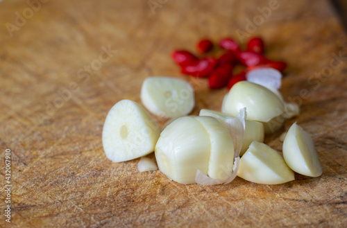 Close up and selective focus shot of peeled garlic and red paprika on cutting board with blurred background shows traditional cuisine for home cooking spice of asian people, especially Thai food.