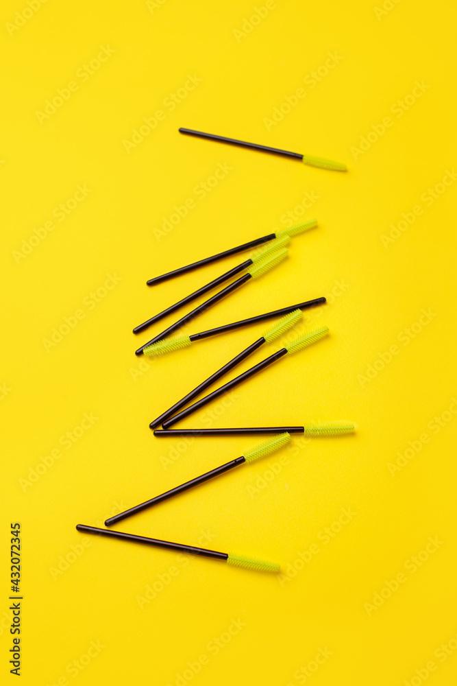 Black green makeup brushes, eyelash combs and eyebrows on trendy bright yellow background with copy space, banner, flyer coupon for lashmakers salon, beutician industry Black green makeup brushes, eyelash combs and eyebrows on trendy bright yellow background with copy space, banner, flyer coupon for lashmakers salon, beutician industry