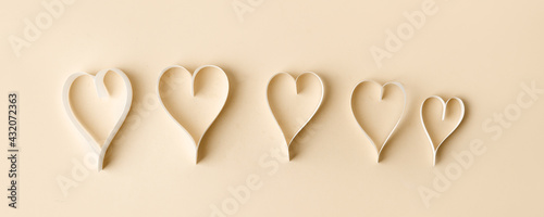 Paper hearts over beige pastel background. Abstract simple background with paper cut shapes. Sainte Valentine, mother's day, birthday wedding greeting cards, invitation, celebration concept, banner