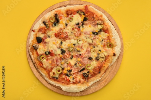 pizza with olives and cheese on yellow background