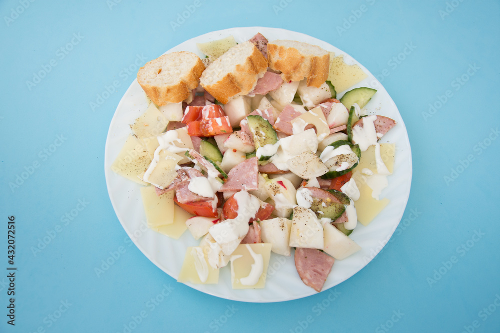 salad with radishes, cheese, tomato pepper cream, cucumber and salami on blue salad with radishes, cheese, tomato pepper cream, cucumber and salami on blue