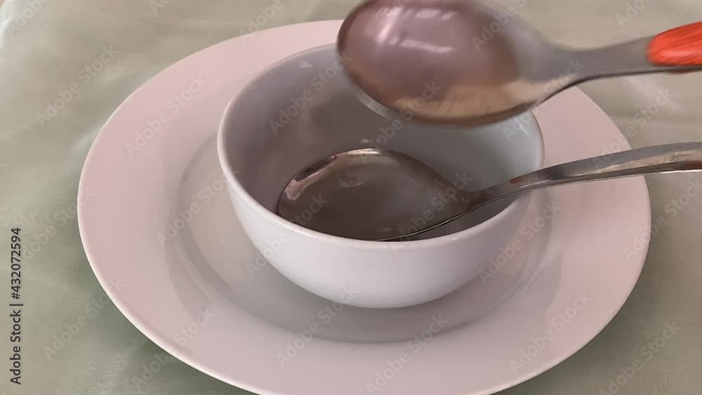 Dish up flat spoons in a bowl in a plate laying the table for dinner Dish up flat spoons in a bowl in a plate laying the table for dinner