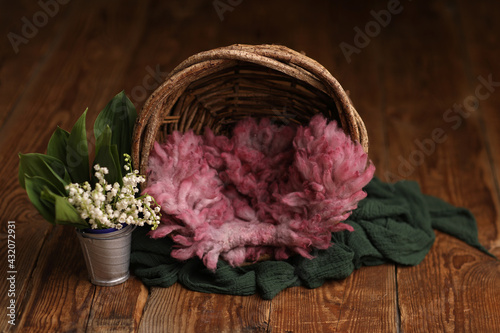 Newborn photography digital background prop. Wood basket with pink fur and flowers on a wooden background