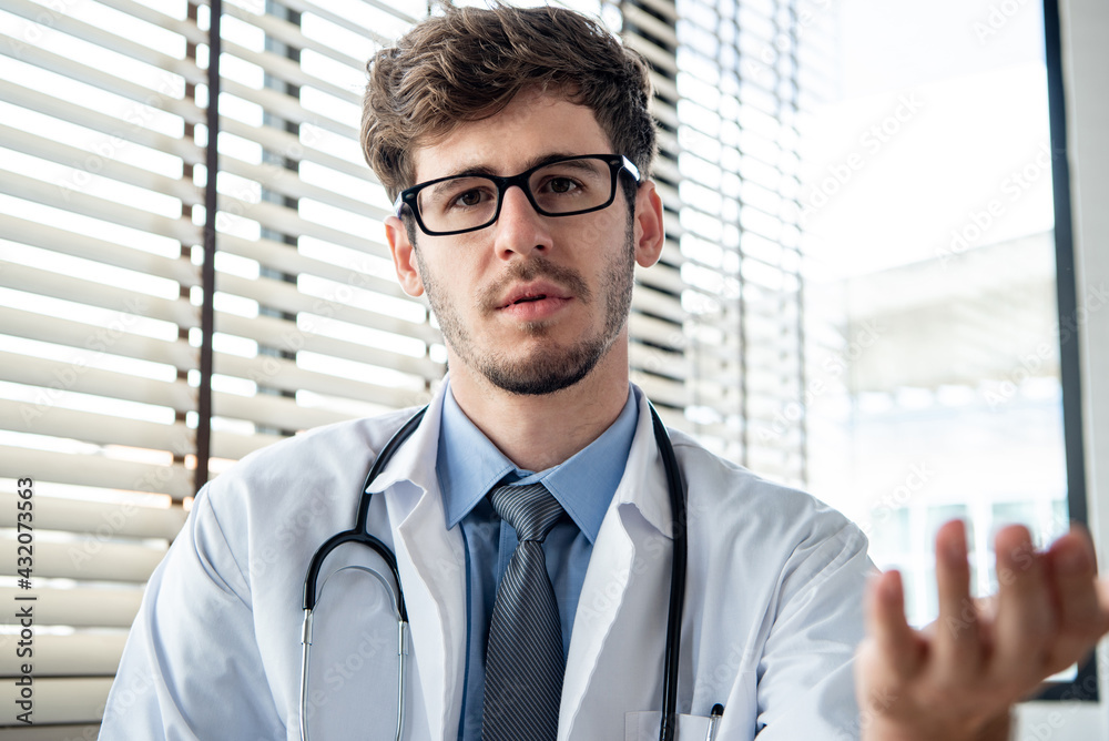 Young male doctor looking at camera explaining and talking with patient online via video calling, distance medical consulting service and telehealth concepts Young male doctor looking at camera explaining and talking with patient online via video calling, distance medical consulting service and telehealth concepts