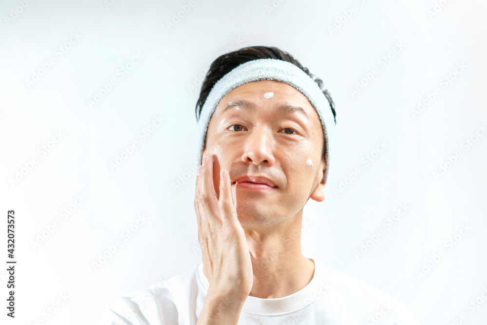 顔にクリームを塗る中年男性 顔にクリームを塗る中年男性