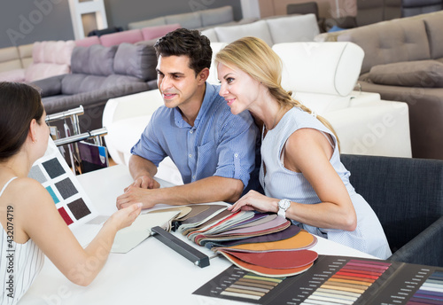 Portrait of family consulting with seler about color for new sofa in shop photo