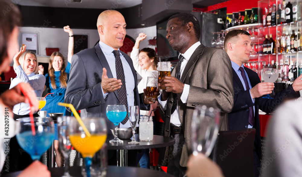 Portrait of African and Caucasian men having fun and talking at corporate party