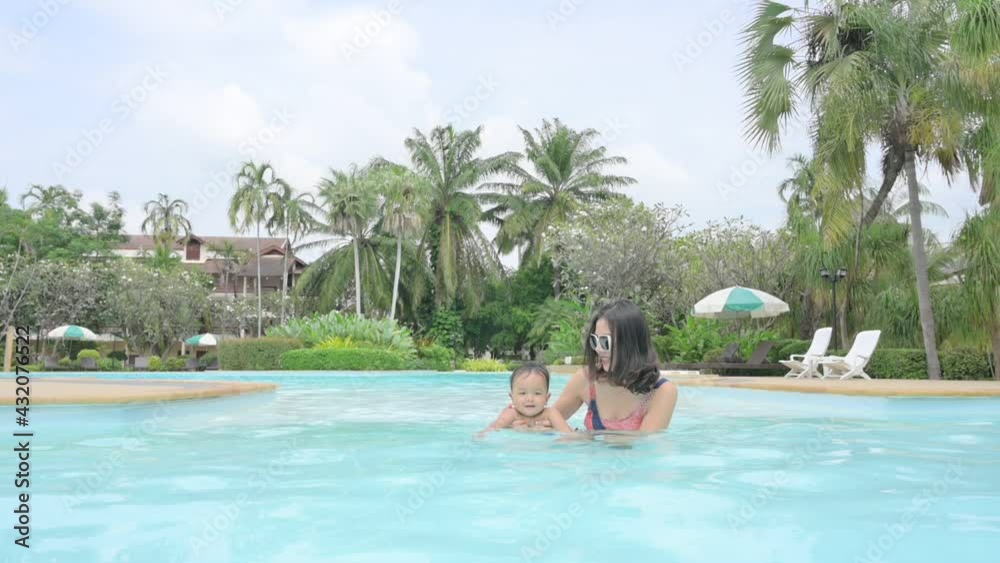 Asian mother and little son enjoying swimming in a swimming pool in summer vacation. Asian mother and little son enjoying swimming in a swimming pool in summer vacation.