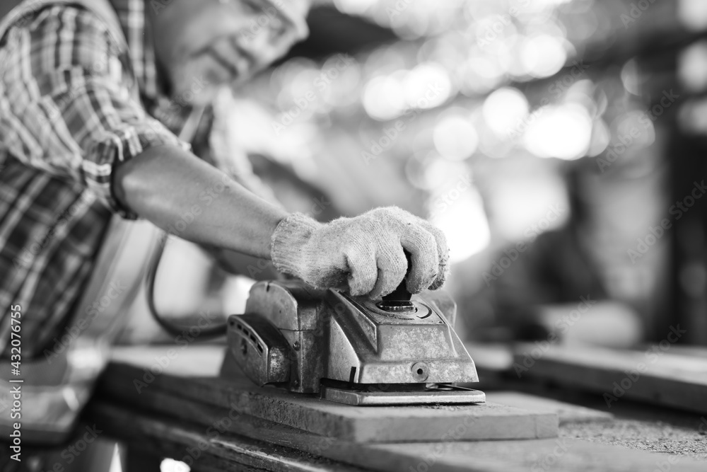 Asian elderly carpenter man working woodwork by electric planer at wood