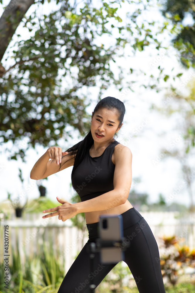 Asian sporty girls dancing with their smartphones at the park. - obrazy, fototapety, plakaty 