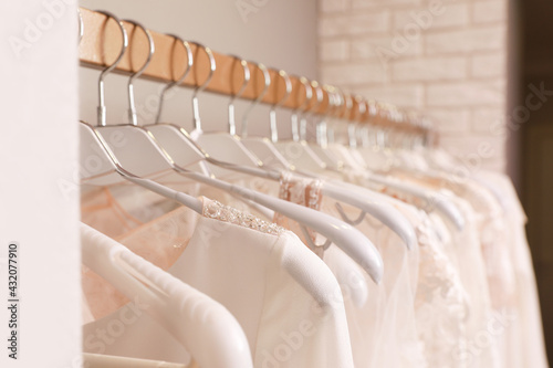 Different wedding dresses on hangers in boutique, closeup