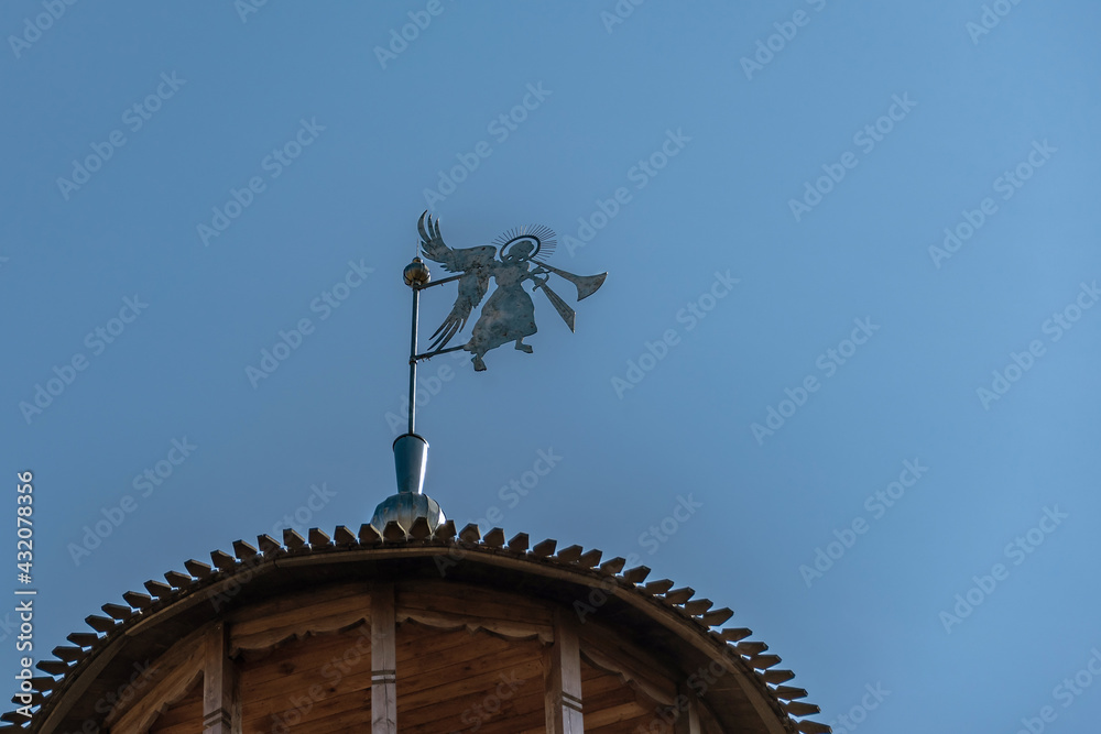 Weather vane in the form of a trumpeting angel on the dome of the tower of an ancient fortress against the sky. Weather vane in the form of a trumpeting angel on the dome of the tower of an ancient fortress against the sky.