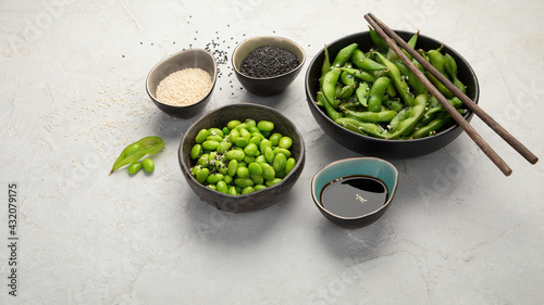Raw edamame soya beans with salt and sauce on light gray background. photo