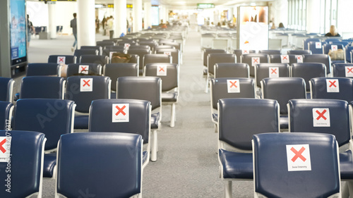 Blurred empty chairs and cross label with social distancing concept for prevention COVID-19 or coronavirus epidemics in terminal at international airport