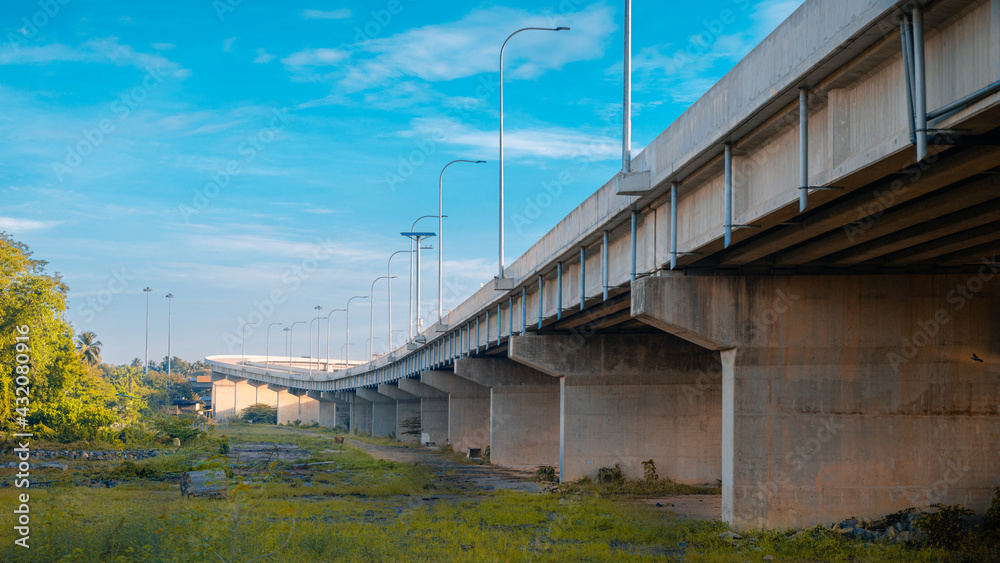 Underneath the elevated Expressway concrete structure, greenery, and clear blue skies landscape view. Underneath the elevated Expressway concrete structure, greenery, and clear blue skies landscape view.