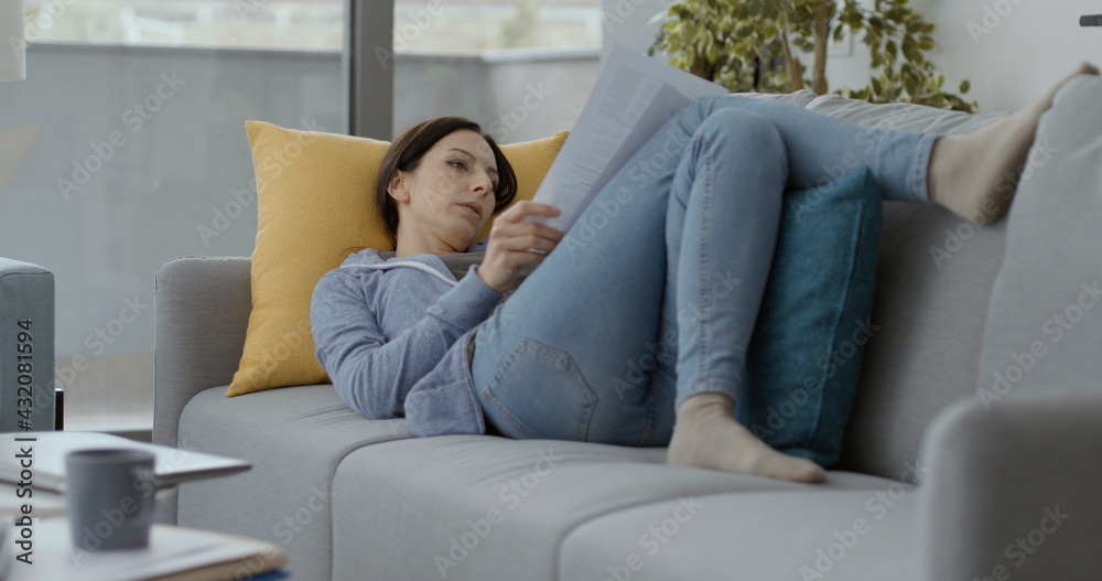 Woman lying on the sofa and checking paperwork