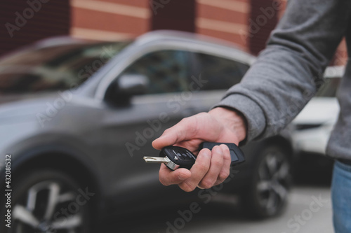 Man in front of the new car and holding keys. Salesman is carrying the car keys delivered to the customer at the showroom with a low interest offer. Rent, credit, insurance, car purchase. Copy space