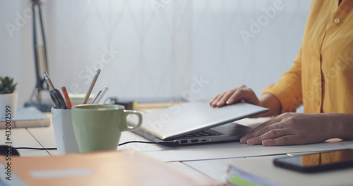 Tableau sur toile Woman sitting at desk and using her laptop