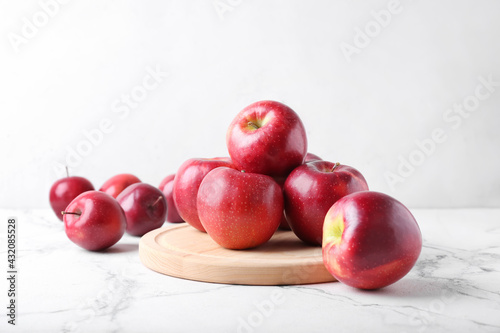 Board with fresh red apples on white background