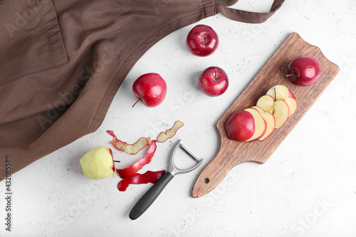 Φωτογραφία Board with cut red apples and peeler on table