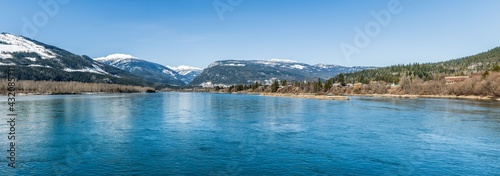 wide Columbia river panorama with snow in mountains blue sky early spring British Columbia Canada