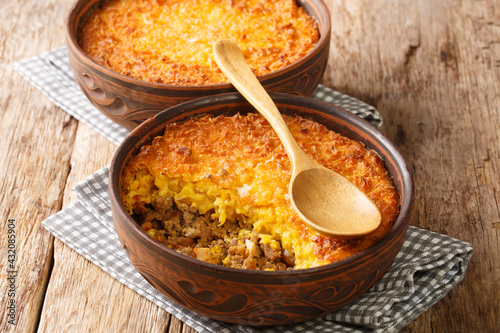 Chilean shepherd's pie, pastel de choclo tops spiced ground beef with a puréed corn crust closeup in the pots on the table. Horizontal