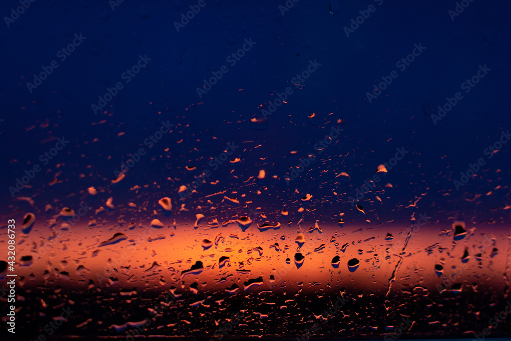 Rain drops on the window on the sunsret (dark-blue pink background)
