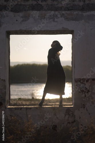 a silhouette of woman in window at sunset photo