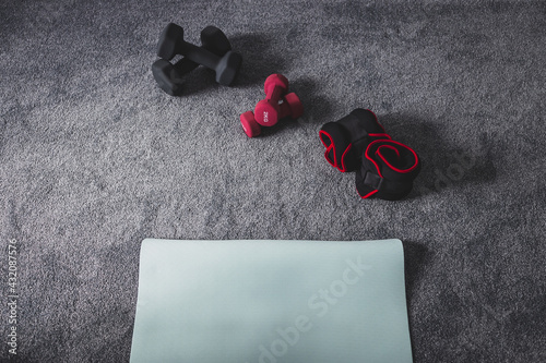 home gym with mixed fitness items including ankle weights and different sets of dumbbells