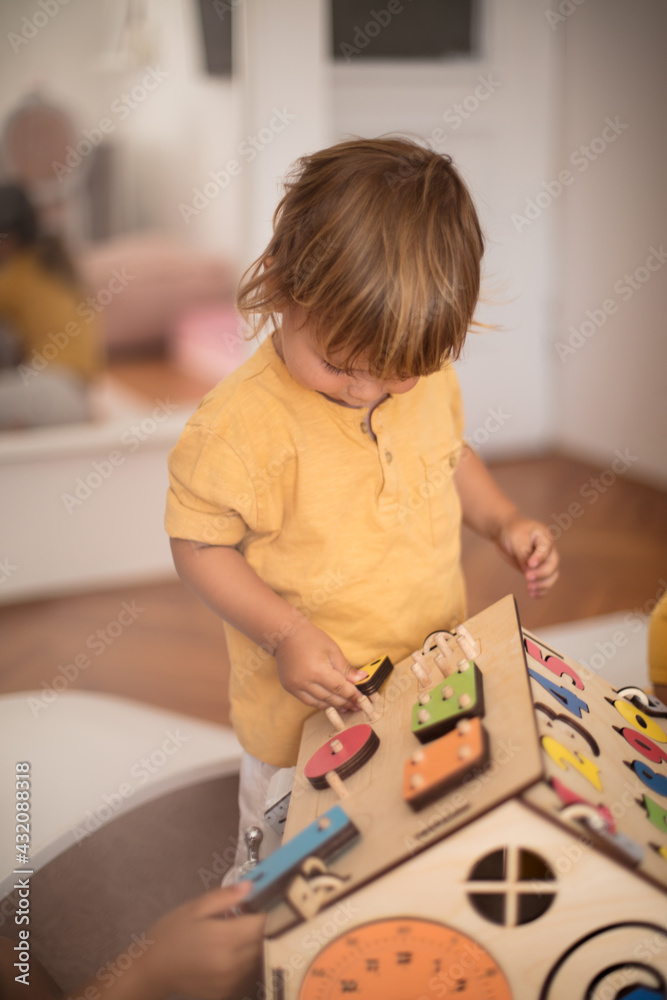 Brother and sister playing in bedroom with wooden toy.