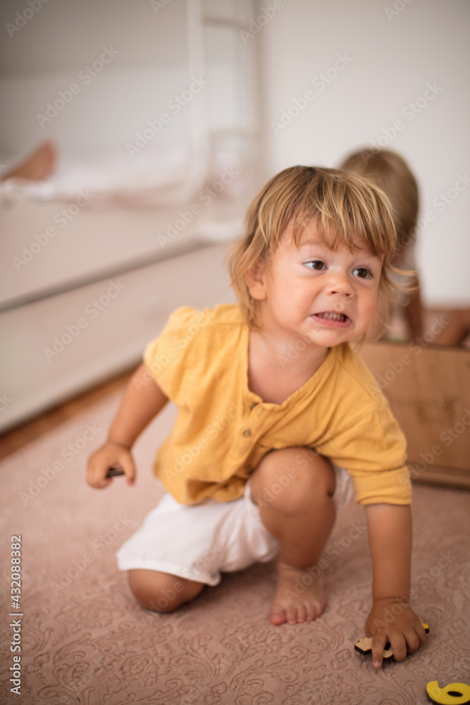 Little brothers brother playing in bedroom. Focus is on foreground. Little brothers brother playing in bedroom. Focus is on foreground.