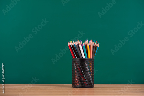 metal cup with pencil on desk on green chalkboard background