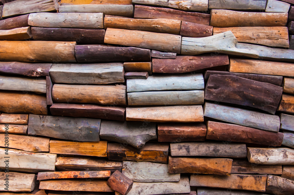 Weathered wall of pieces of logs screwed with screws.