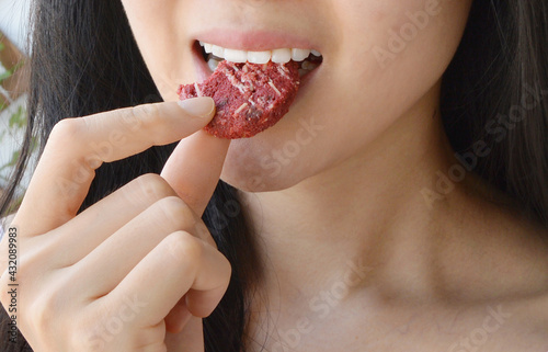 Young woman eating a red velvet cookie