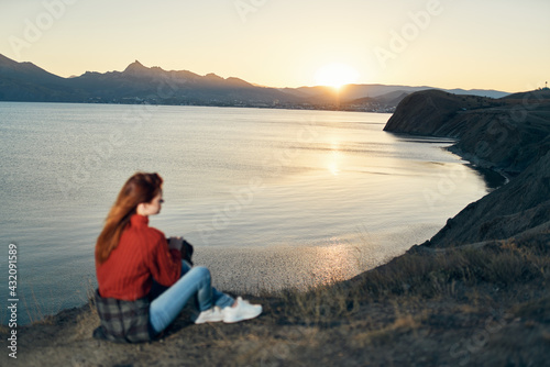woman sits on the ground in nature in the mountains near the sea adventure sunset
