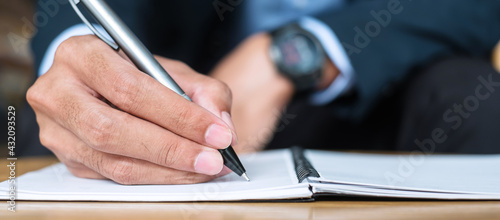 Wallpaper Mural Businessman in suit writing something on notebook in office or cafe, hand of man holding pen with signature on paper report. business concepts Torontodigital.ca