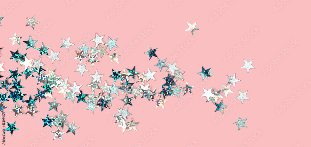 scattered siler holographic glitter confetti star shaped on candy pink background Flat lay top view copy space. Festive holiday pastel backdrop. Birthday, giveaway, Christmas, New Year