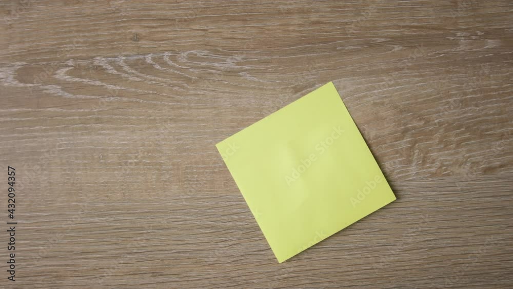 Female hand stick yellow note on wooden surface, write down DO NOT GIVE UP with red pen. Close up, top view 