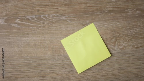 Female hand stick yellow note on wooden surface, write down DO NOT GIVE UP with red pen. Close up, top view 