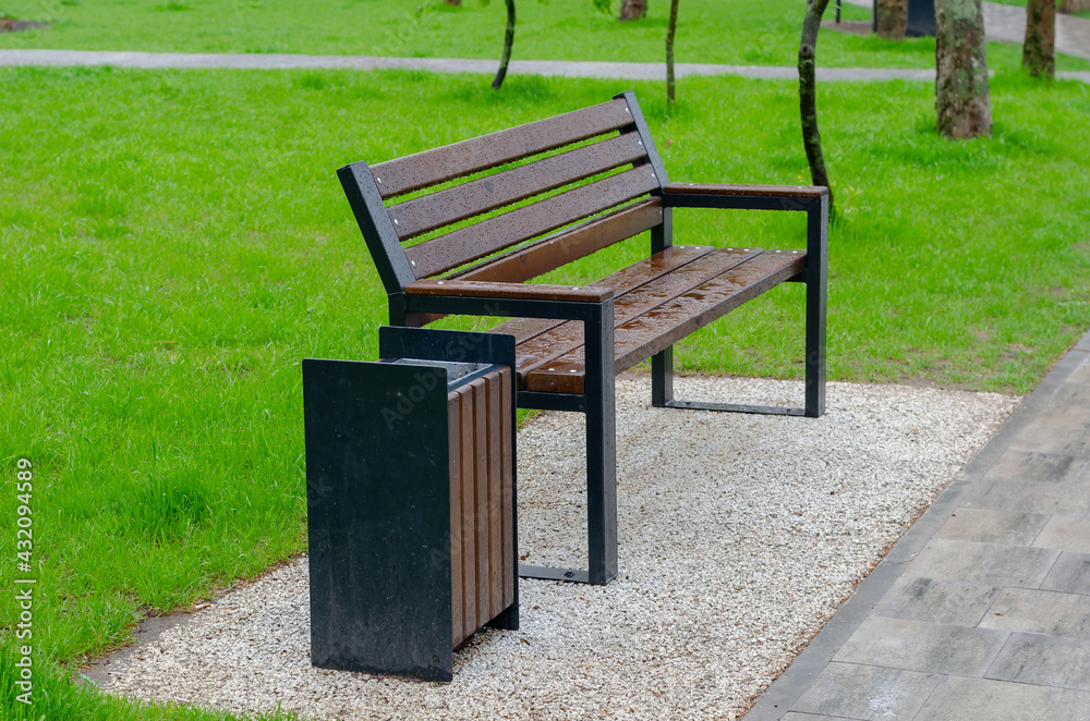 Wet empty park bench against the backdrop of a green lawn. Wet empty park bench against the backdrop of a green lawn.